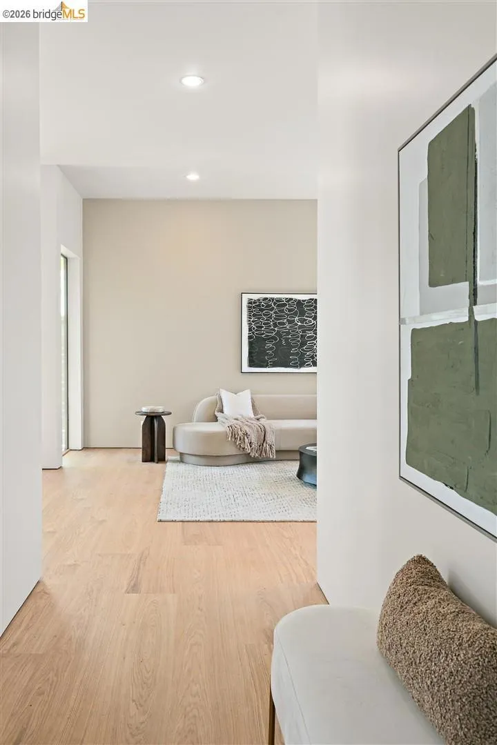Open-concept living area with light wood-finish flooring, recessed lighting, and neutral wall tones
