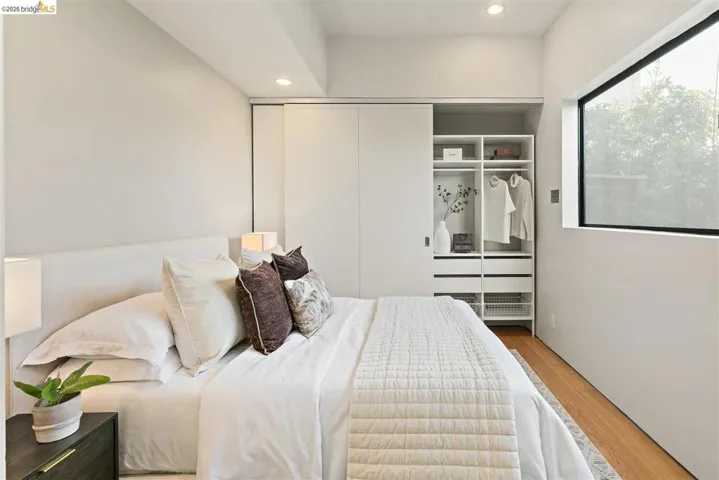 Bedroom featuring a built-in closet system with sliding doors, a large rectangular window, and recessed ceiling lighting