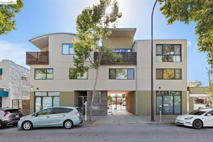 Modern multi-story building featuring a neutral stucco facade and dark-framed windows