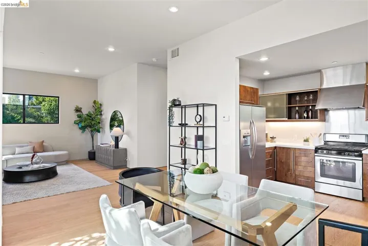 Open-concept living space featuring wood-finish flooring, recessed lighting, and a kitchen with stainless steel appliances, wood-finish cabinetry, and under-cabinet lighting