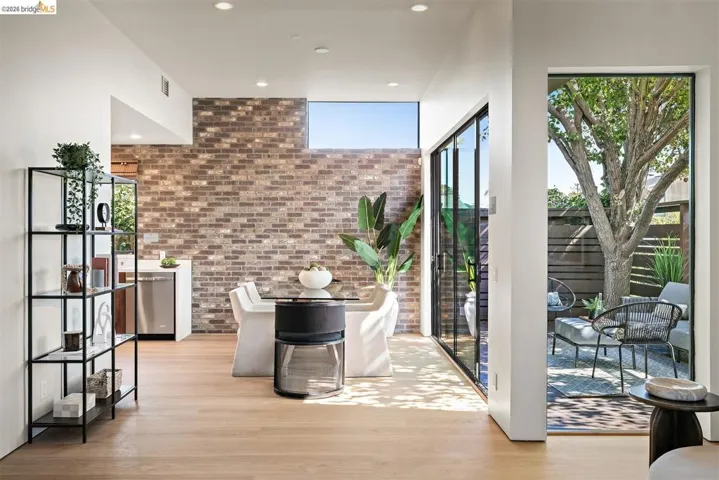 Open-concept interior featuring light wood-finish flooring, a brick accent wall, and recessed lighting