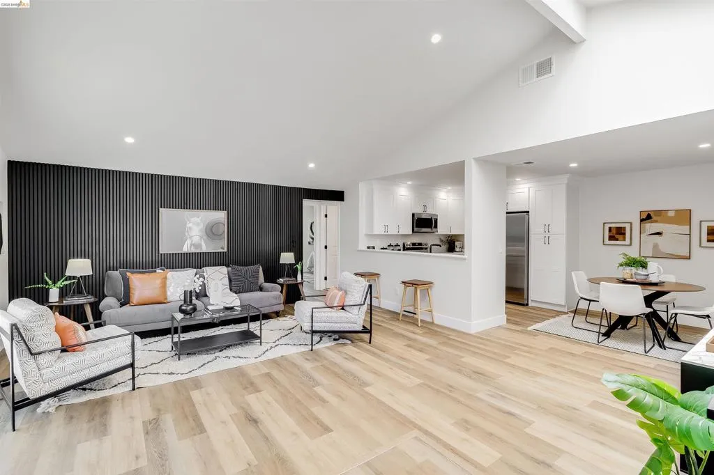 Spacious living area featuring a vaulted ceiling and light wood-finish flooring