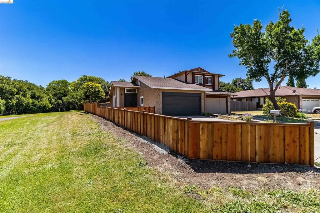 Two-story property featuring a warm-toned exterior, an attached garage, and a new privacy fence