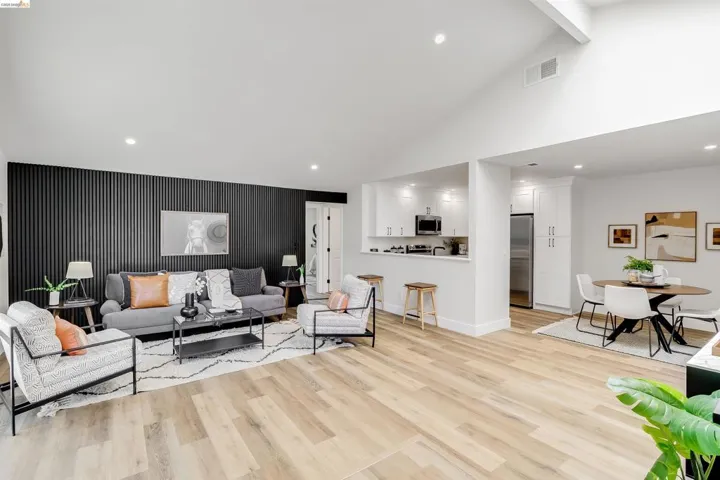 Spacious living area featuring a vaulted ceiling and light wood-finish flooring
