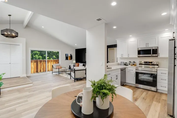 Open-concept kitchen and living area featuring wood-finish flooring throughout, a vaulted ceiling, and recessed lighting
