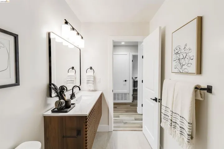 Bathroom featuring a wood-finish vanity with slat detailing and a white countertop, complete with a rectangular mirror and black wall-mounted faucet