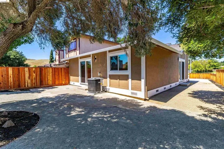 Rear exterior featuring a brown stucco finish with white trim, a wood privacy fence, and multiple sliding glass doors