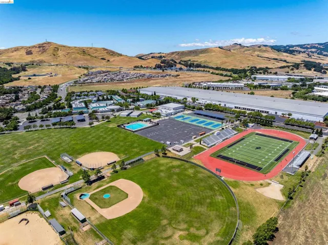 Expansive athletic complex featuring multiple baseball diamonds, a track and field stadium, tennis courts, and a swimming pool