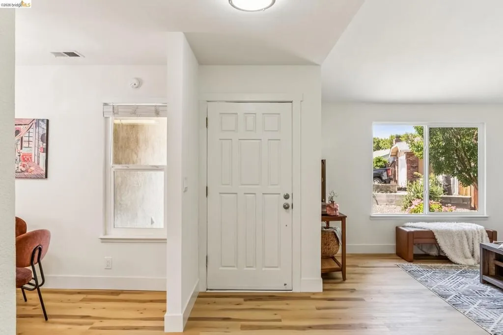 Entryway featuring a paneled door, wood-finish flooring, and white trim throughout
