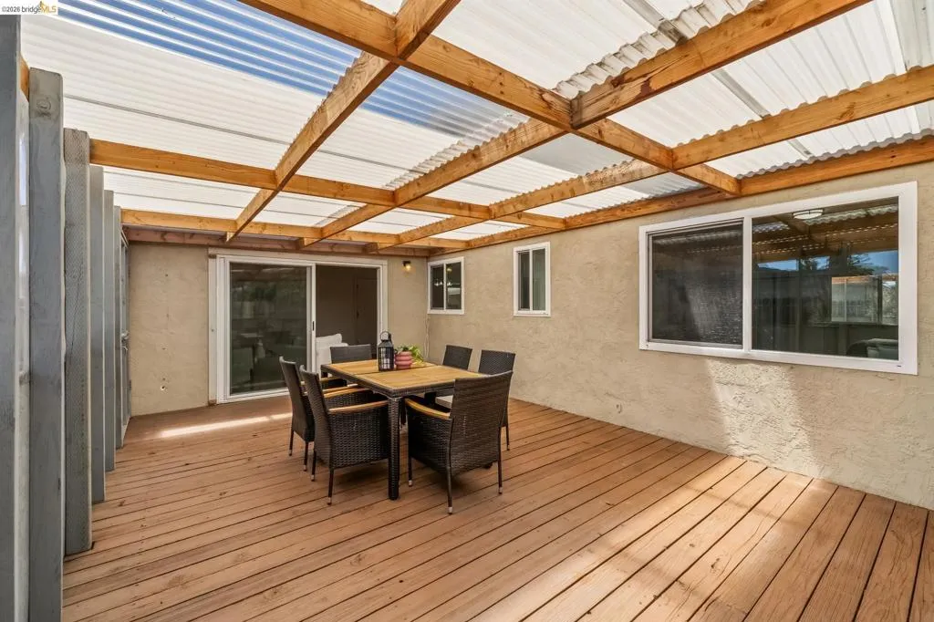 Covered outdoor patio featuring wood-finish decking and a translucent corrugated roof supported by exposed wood beams