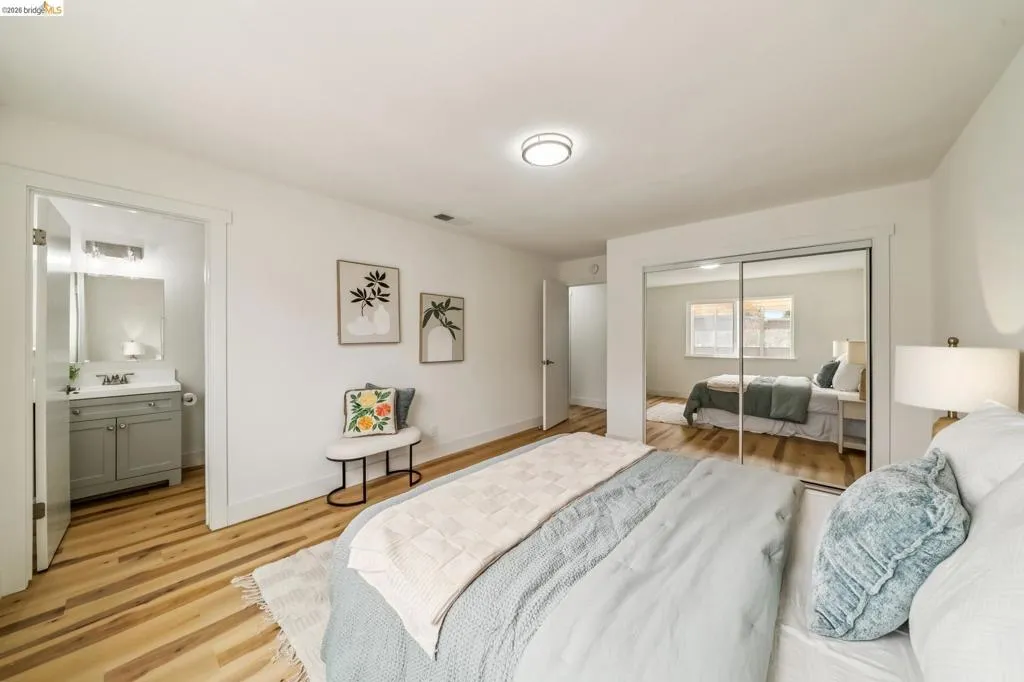 Bedroom featuring wood-finish flooring, mirrored closet doors, and a ceiling-mounted light fixture