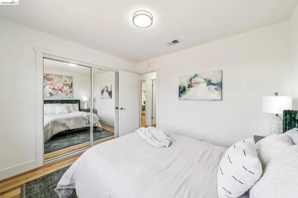 Bedroom featuring wood-finish flooring, a contemporary ceiling light fixture, and a mirrored sliding closet door
