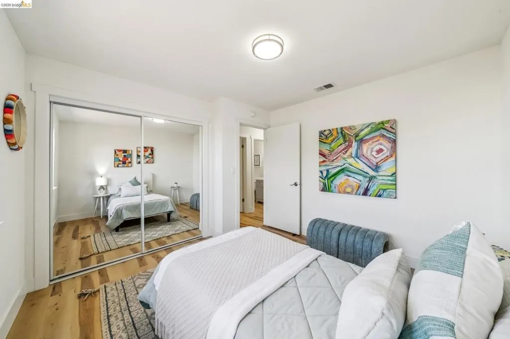 Bedroom featuring wood-finish flooring, white walls, and a ceiling-mounted light fixture