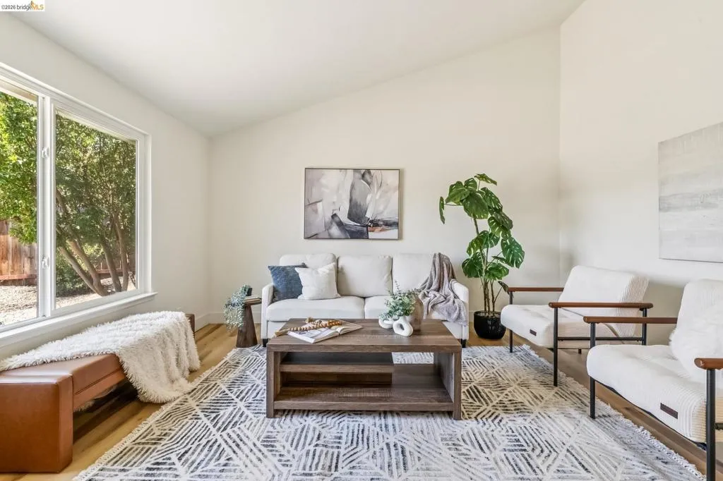 Spacious living area featuring a vaulted ceiling and light wood-finish flooring