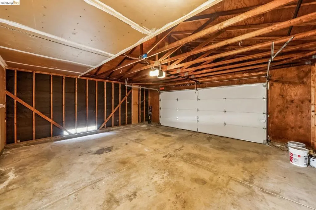Spacious garage featuring a concrete floor, exposed wood ceiling joists, and a sectional overhead door