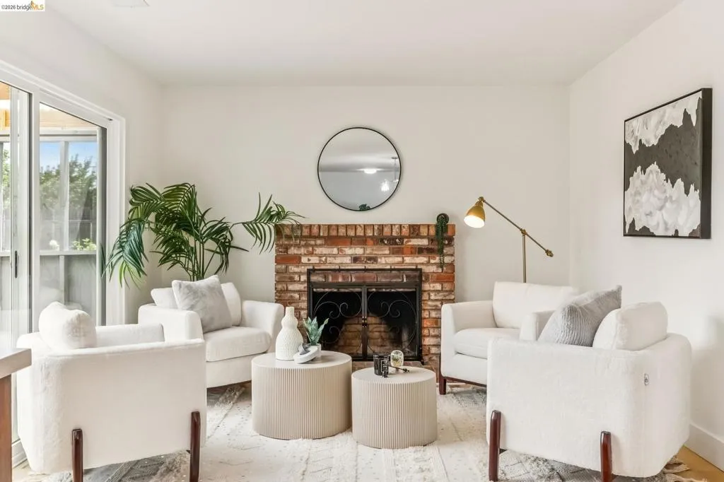 Brick fireplace with dark metal grate, light-toned walls, and wood-finish flooring