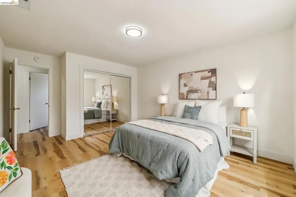 Bright interior featuring wood-finish flooring, a mirrored closet, and a flush-mount ceiling light fixture