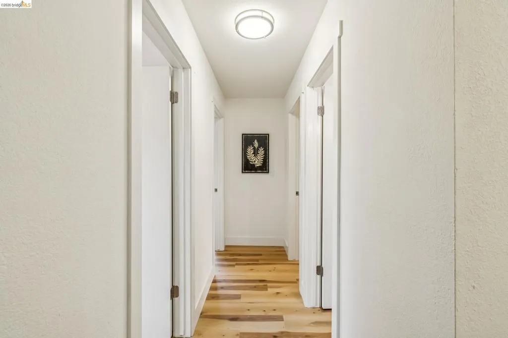 Hallway featuring light wood-finish flooring, white walls, and multiple doorways