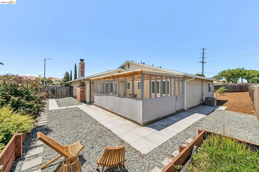 Rear exterior featuring a covered patio structure, stucco siding, and a brick chimney