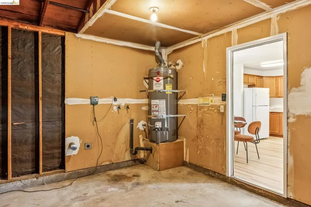 Utility room with a water heater installation and concrete flooring