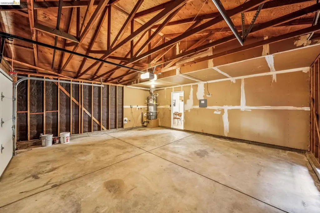 Spacious garage with exposed wood beam ceiling, concrete flooring, and an overhead garage door