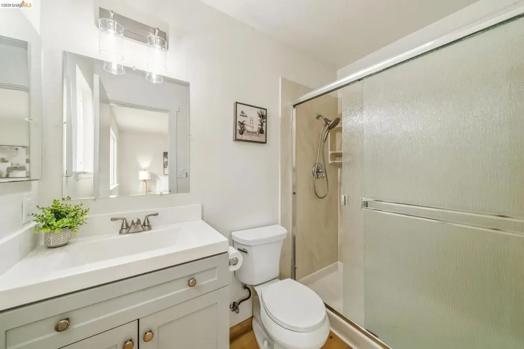 Bathroom featuring a light-toned vanity with a white countertop and integrated sink, brushed nickel faucet, and a wall-mounted mirror with overhead lighting