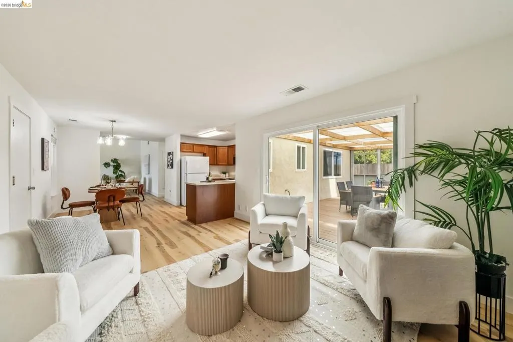 Open-concept living area featuring light wood-finish flooring, a dining area with pendant lighting, and a kitchen with wood cabinetry