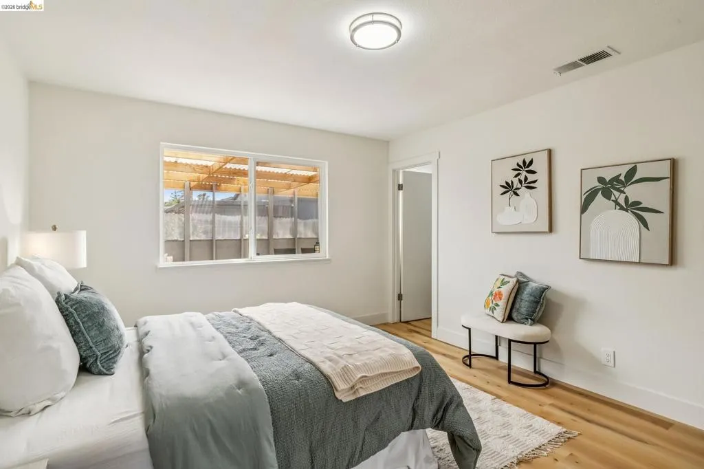Bedroom featuring wood-finish flooring, a white trim baseboard, and a white ceiling with a flush-mount light fixture