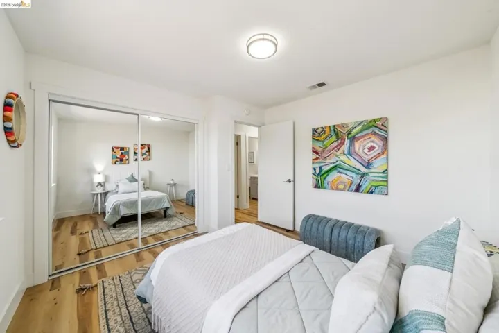 Bedroom featuring wood-finish flooring, white walls, and a ceiling-mounted light fixture