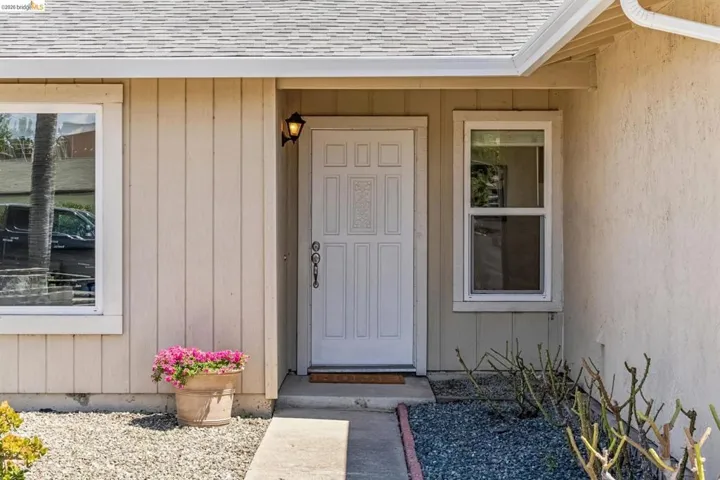 Entryway featuring a paneled door with decorative glass, an exterior wall sconce, and a concrete pathway