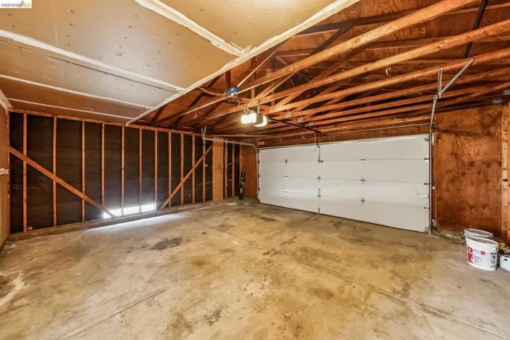 Spacious garage featuring a concrete floor, exposed wood ceiling joists, and a sectional overhead door