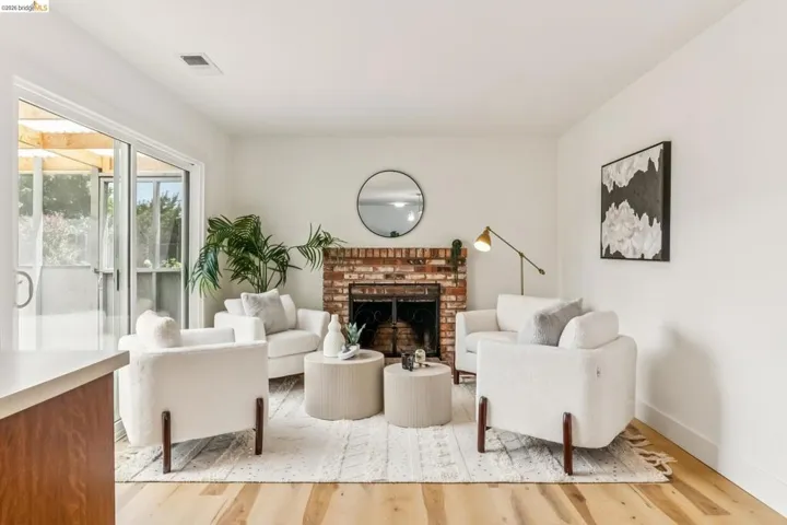 Living area featuring a brick fireplace, light wood-finish flooring, and white walls