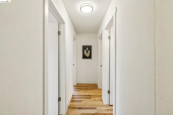 Hallway featuring light wood-finish flooring, white walls, and multiple doorways