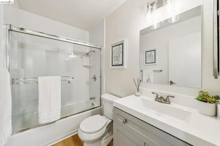 Bathroom featuring a single vanity with an integrated sink, brushed nickel faucet, and light gray cabinetry