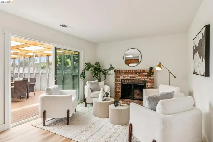 Living area featuring a brick fireplace, wood-finish flooring, and white walls