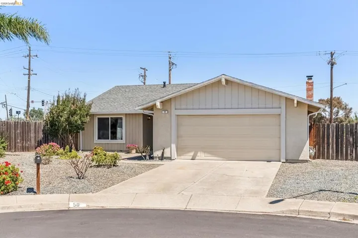 Single-story residence featuring a two-car garage, concrete driveway, and gravel landscaping