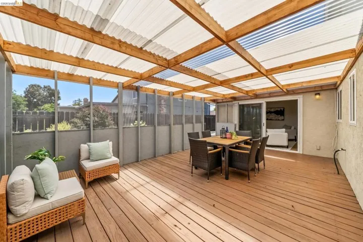 Expansive wood-finish deck with a translucent corrugated roof supported by exposed wood beams