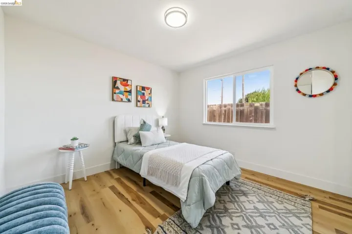 Bright interior room featuring wood-finish flooring, white walls, and a large window