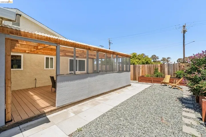 Covered patio with wood-finish decking, stucco exterior, and corrugated roof