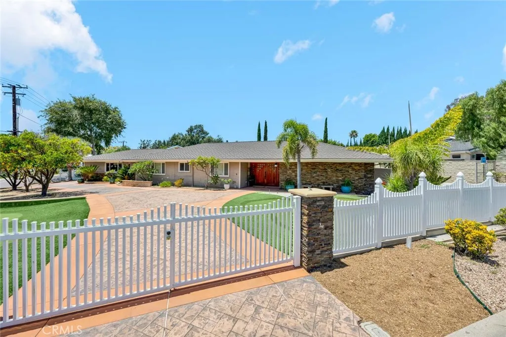 Single story home with sweeping circular drive and two entrances and   gates.