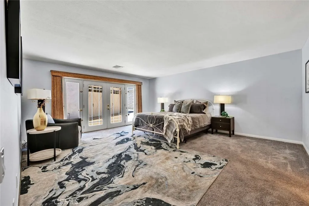 Primary suite shows large spacious room and French doors to outside.
