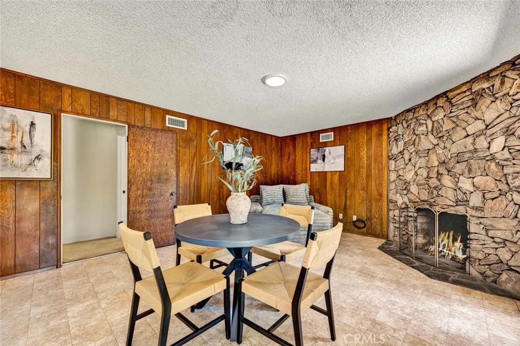 Family room shows rock fireplace wall and wood paneling.