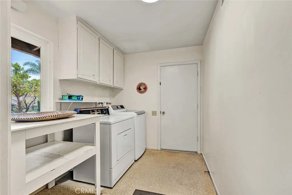 Laundry room with electrical and gas hook-ups.  folding/storage table, upper cabinets and door leading to separate
two-car garage with its own driveway and gate.