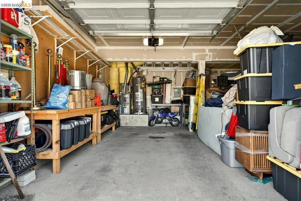 Spacious garage featuring a concrete floor, built-in wooden workbench, and metal shelving units