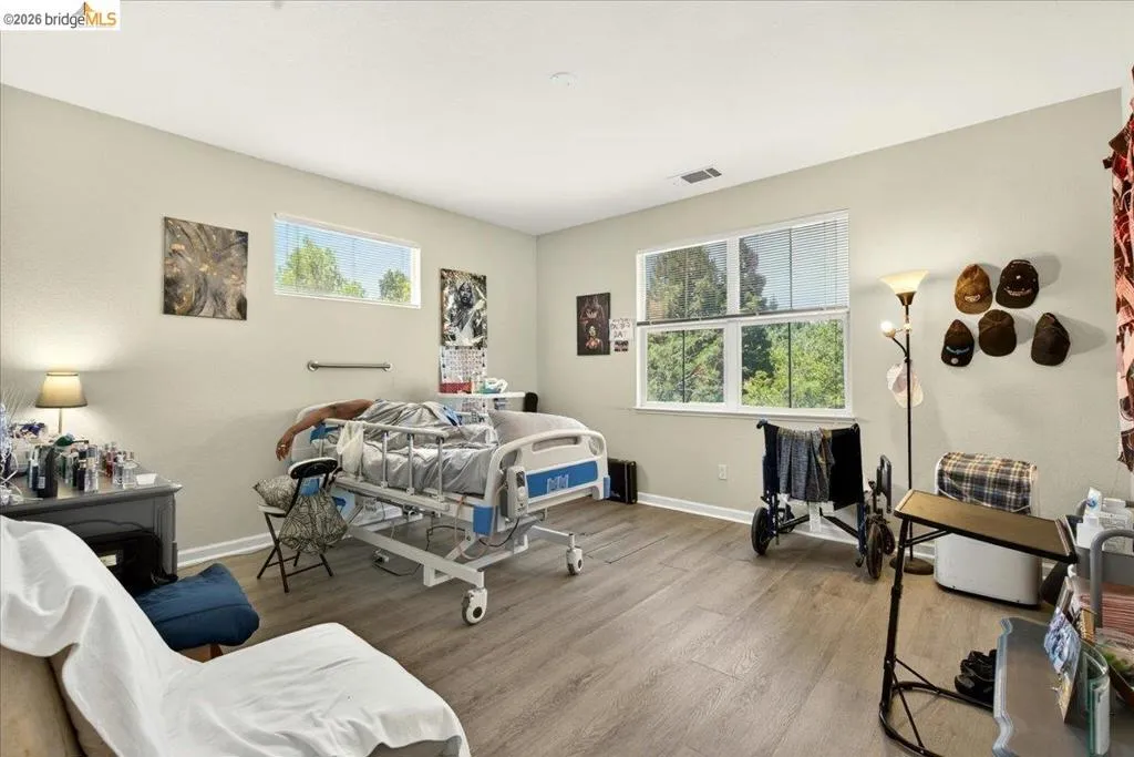Spacious room featuring wood-finish flooring, light-toned walls, and multiple windows