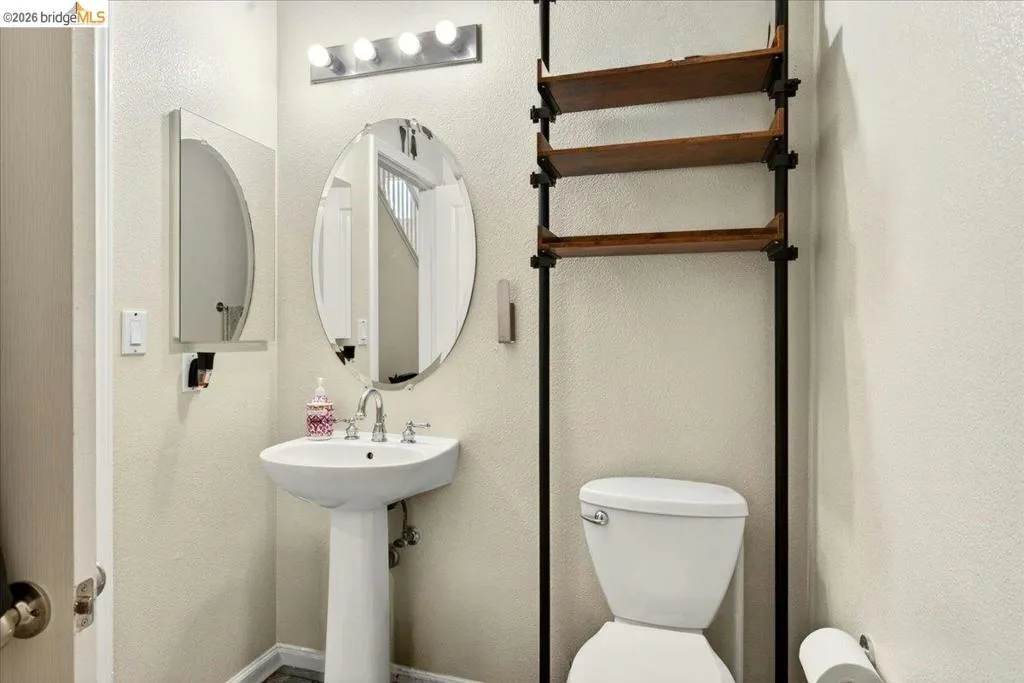 Pedestal sink with chrome faucet, an oval mirror, and a wall-mounted medicine cabinet