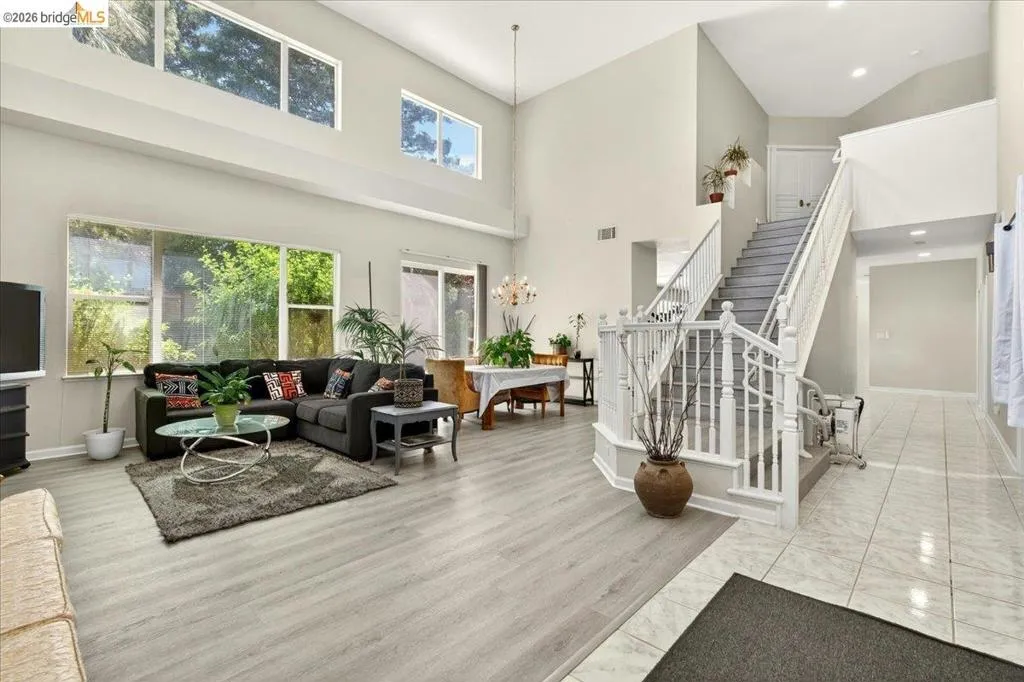Vaulted ceilings in a living area featuring wood-finish flooring, a large window bank, and a sliding glass door