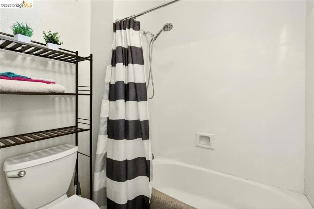 White bathtub and shower combination with a wall-mounted shower head and built-in soap dish