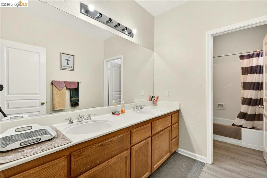 Dual vanity with wood-finish cabinetry and a white countertop, featuring two undermount sinks and chrome fixtures