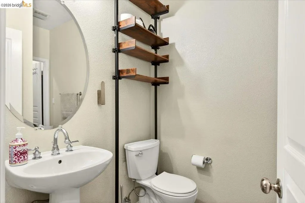 Pedestal sink with chrome fixtures and an oval mirror